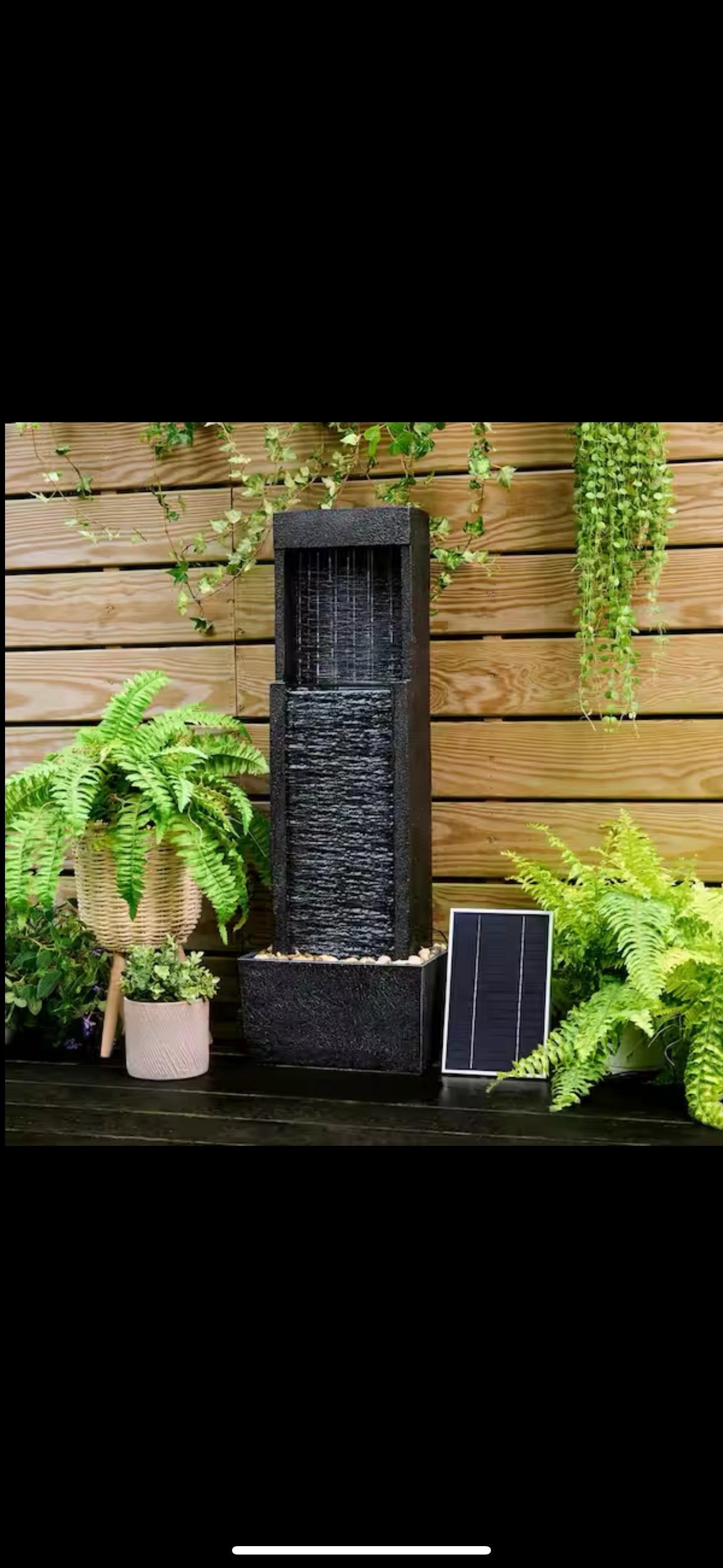 38-inch solar-powered gray slate waterfall fountain with LED lights surrounded by potted plants and greenery.