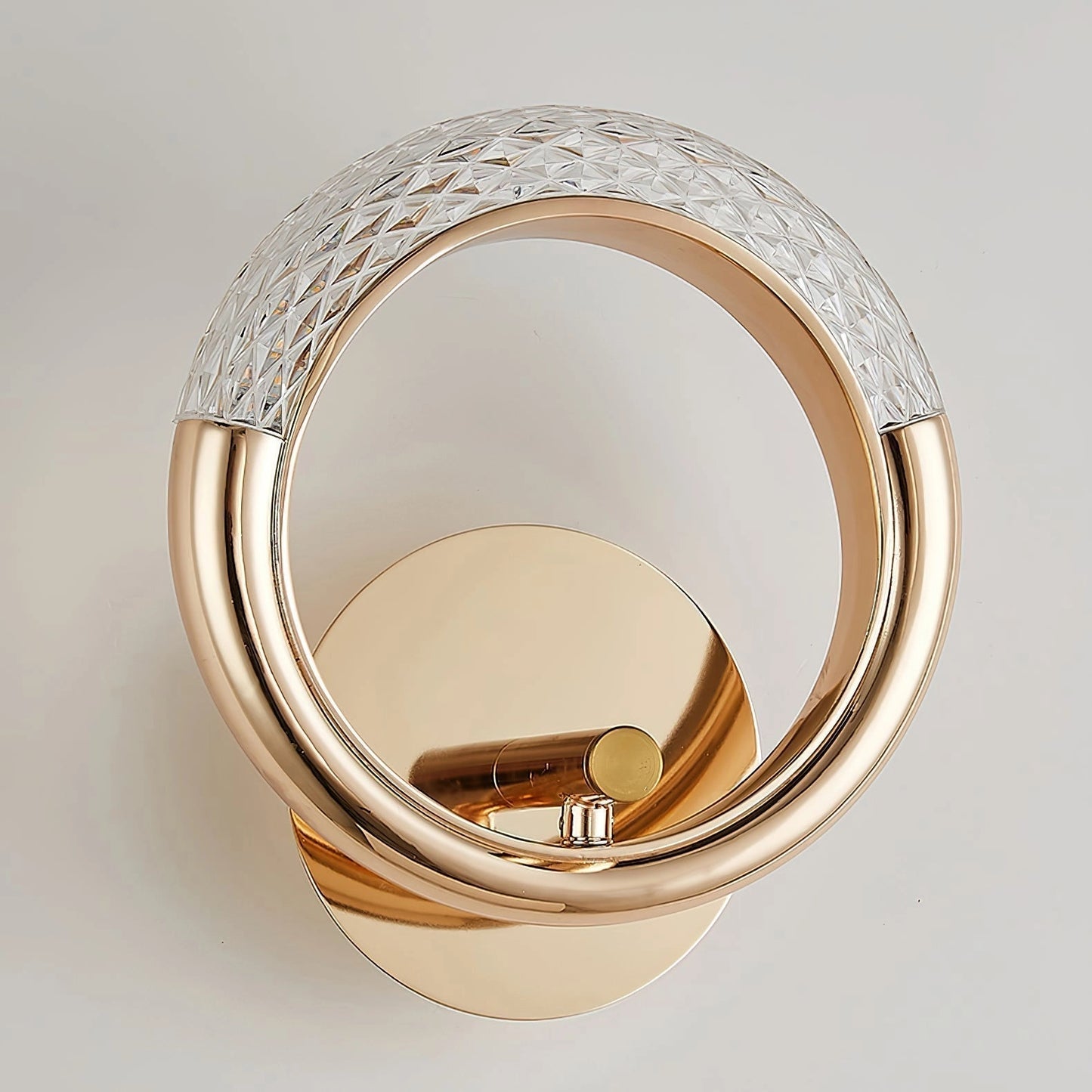 Luxurious metallic adaptable angle rotatable wall lamp with sleek design, mounted on a wooden surface, featuring a circular base and a polished finish.