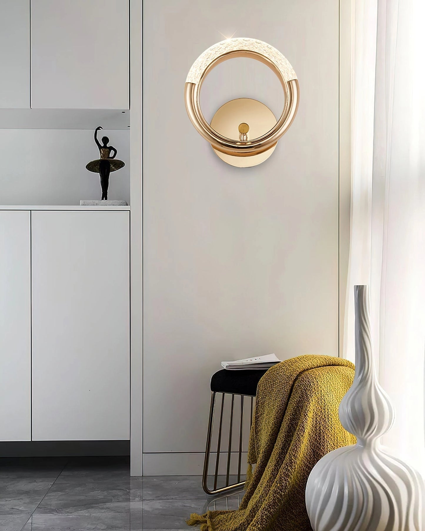 Luxurious metallic wall lamp with an adaptable, angle-rotatable design, mounted on a wall, illuminating an interior space with warm yellow light.