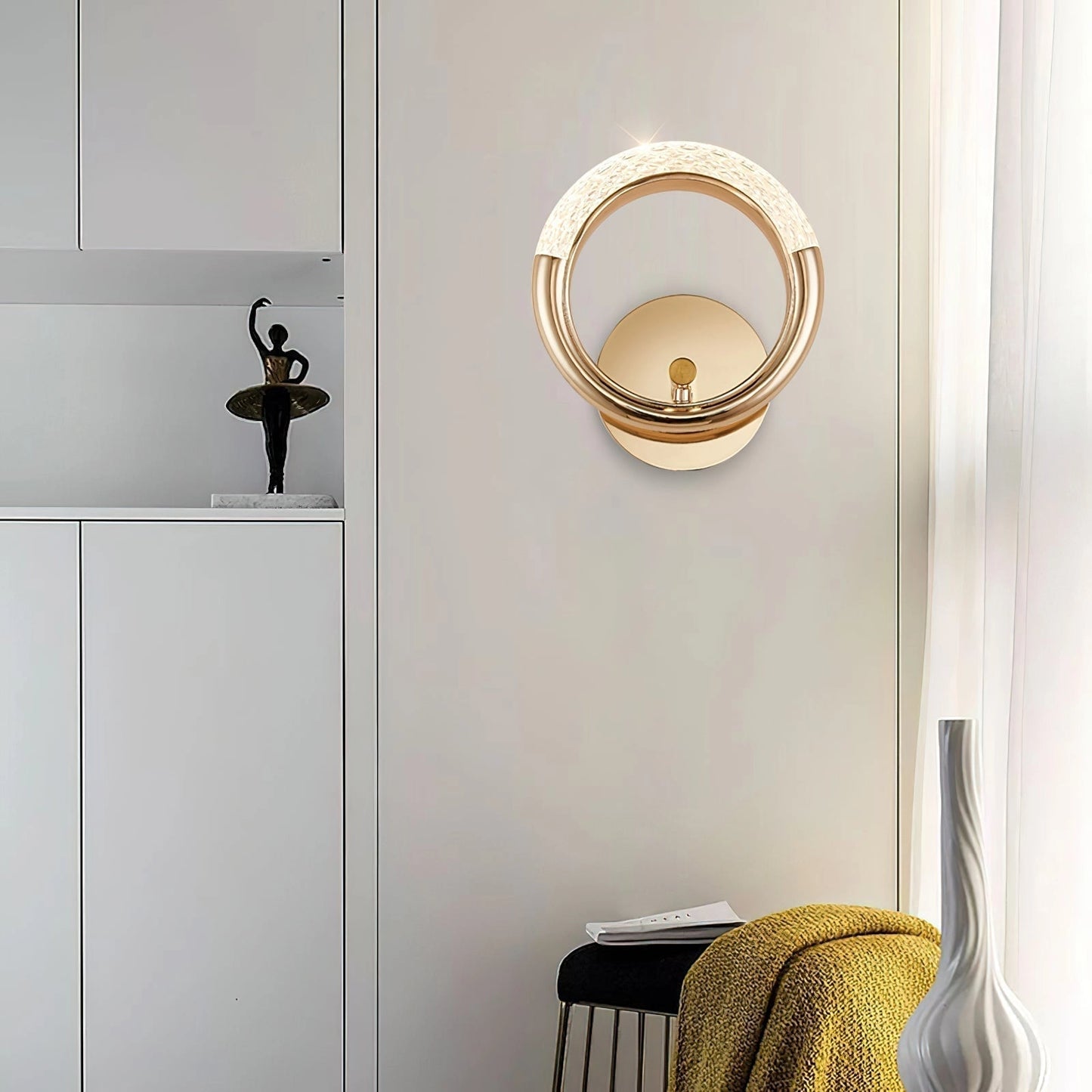 Luxurious metallic wall lamp with an adaptable angle and rotatable design, mounted on a white wall in a modern interior setting.