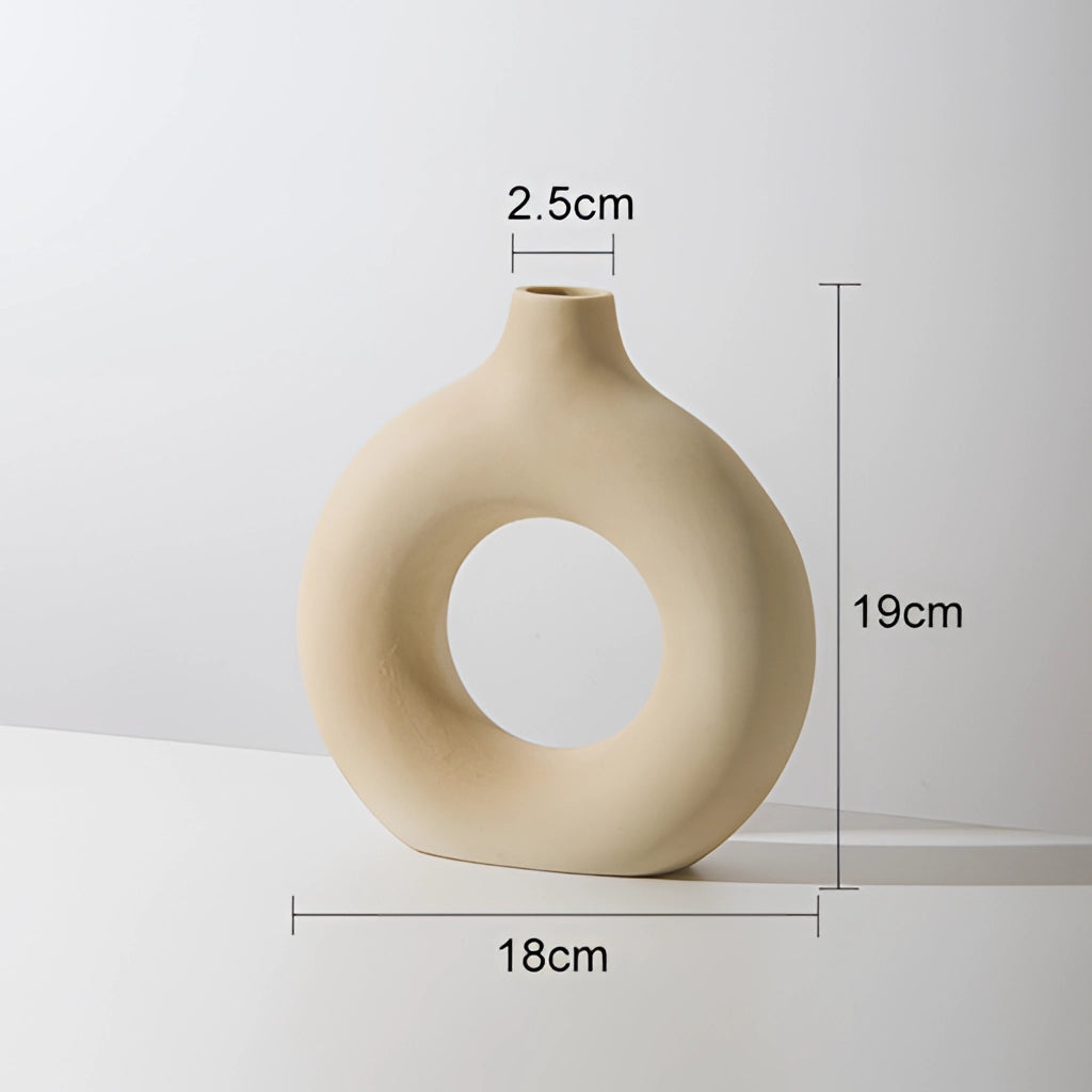 Beige ceramic donut-shaped vase for modern home decor.
