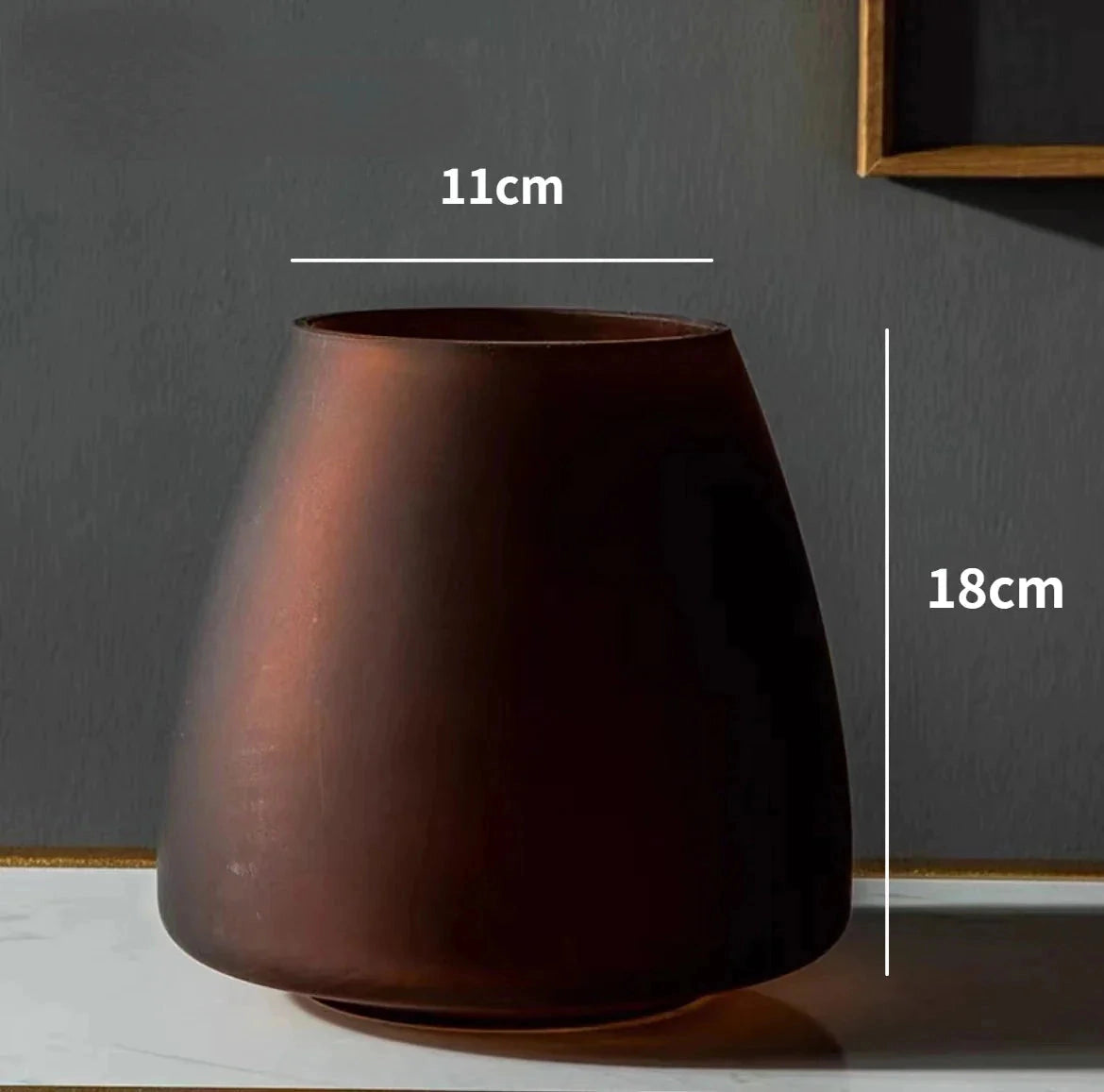 Coffee-colored frosted glass vase on a wooden surface with a minimalist design.