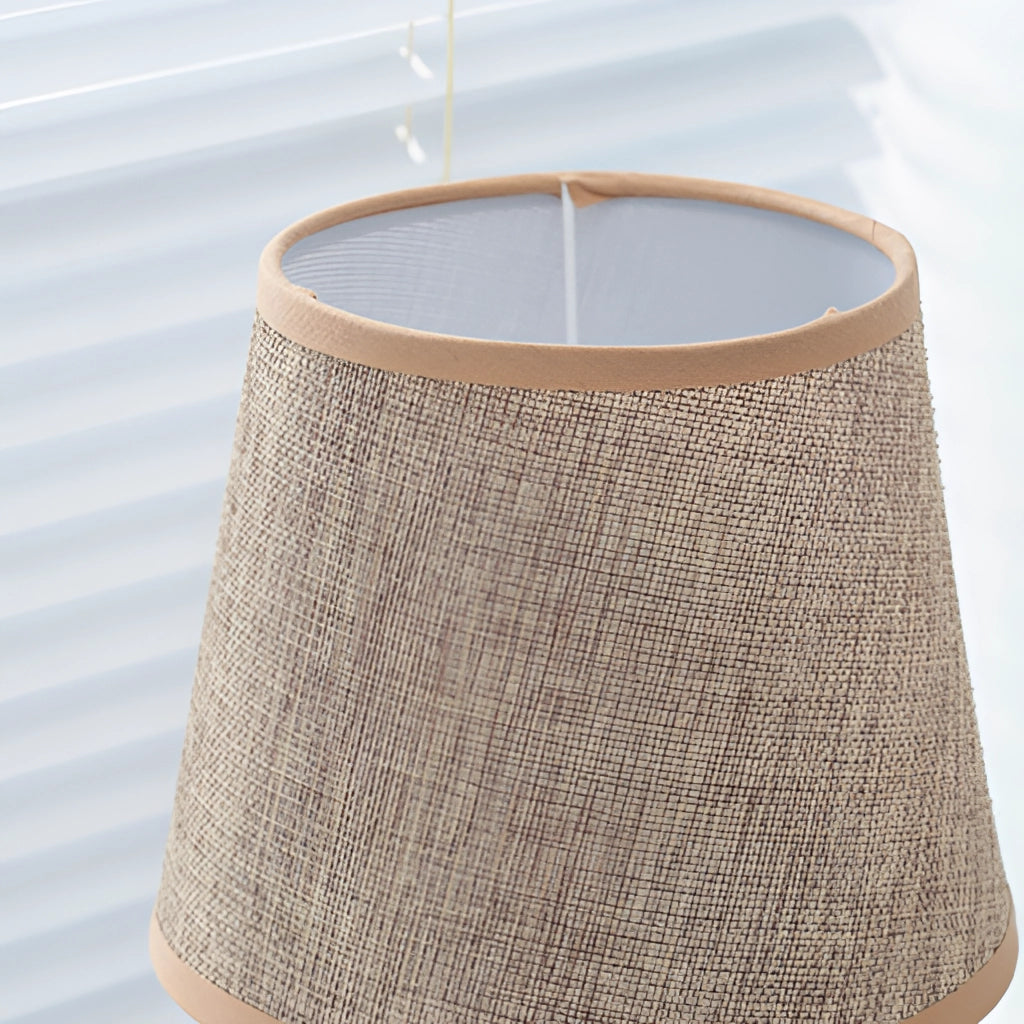 Contemporary fabric lampshade on a wooden desk next to a chair, featuring a beige rectangular design suitable for a nightstand or desk.