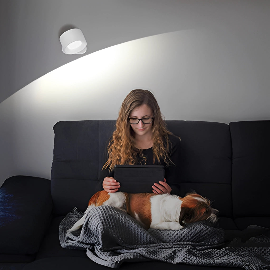 A person sitting comfortably on a couch with a cordless LED wall lamp illuminating the room, showcasing adjustable brightness and color modes.
