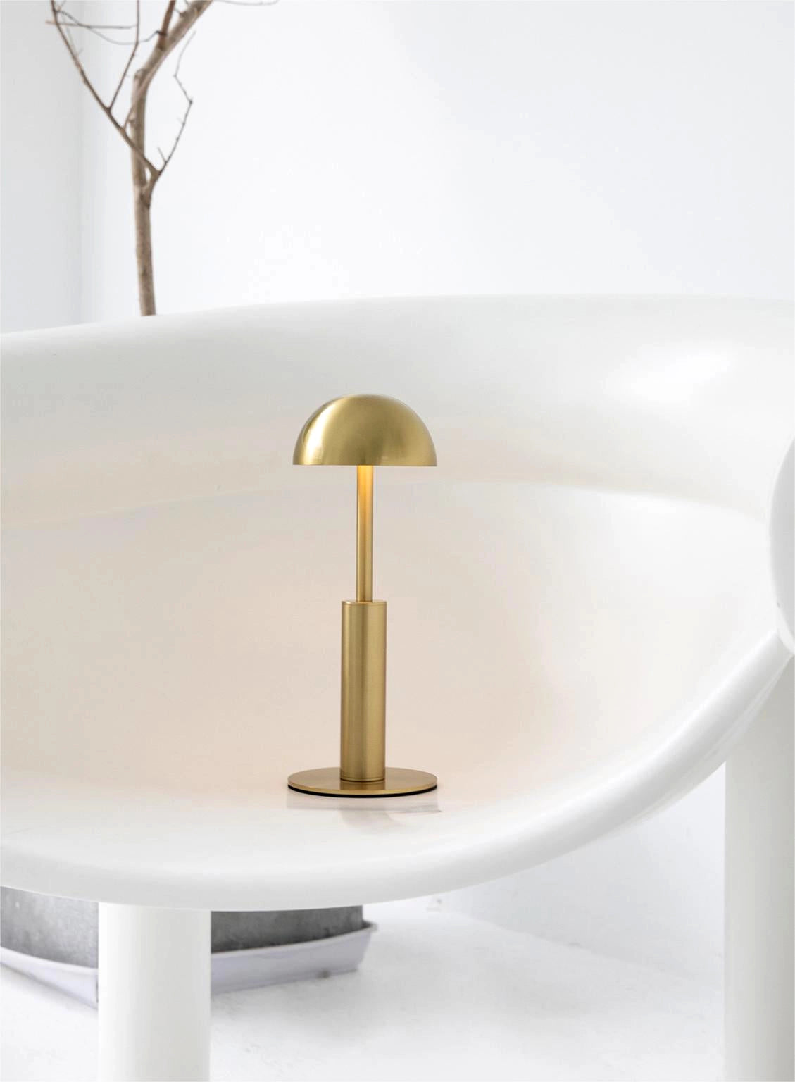 Cordless rechargeable table lamp with unique sculptural design, featuring a wooden base and rectangular frame, displayed on a shelf with natural materials and artistic elements.