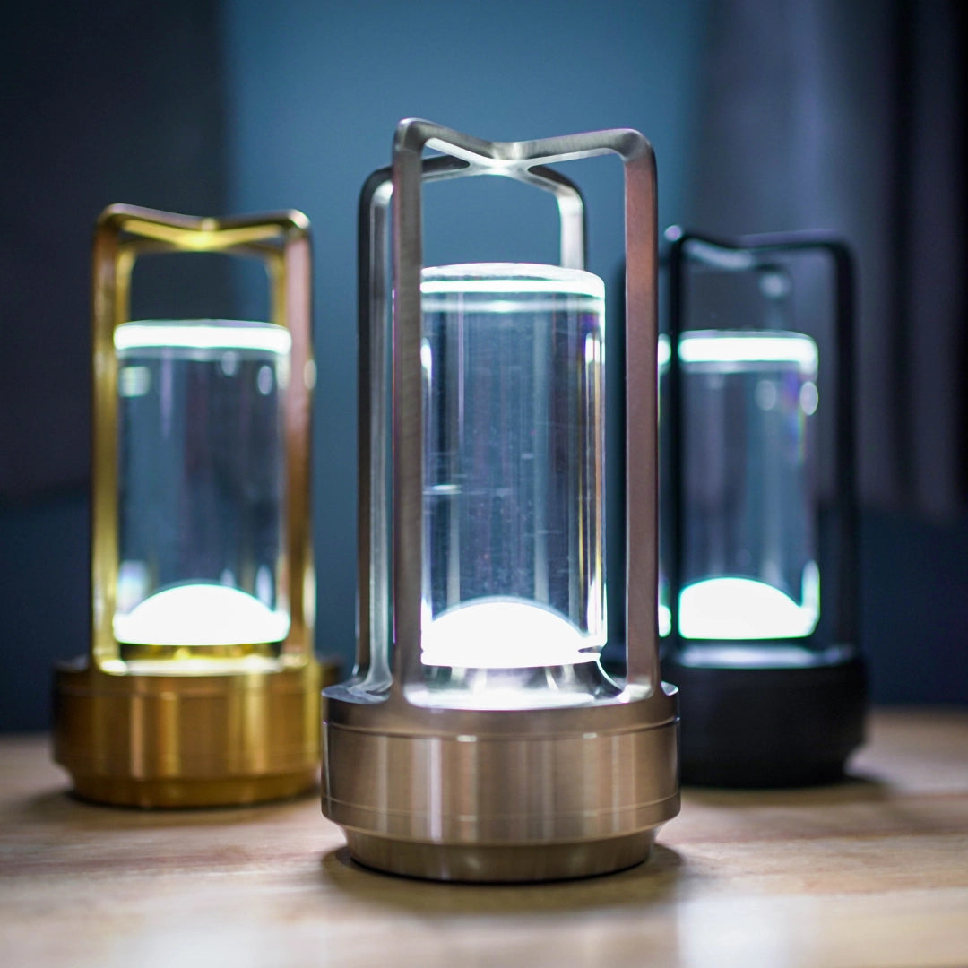 A crystal lantern table lamp with a touch sensor, featuring a wireless LED light and cylindrical transparent design, made of glass and aluminum with a modern electric blue finish.
