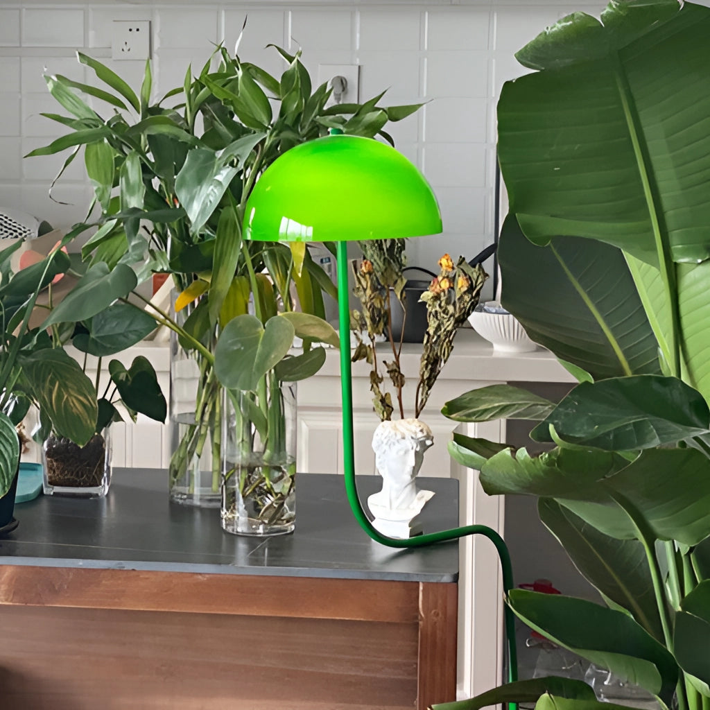 Floor lamp with organic inspiration featuring a green and white tricolor light, placed in a room with houseplants and wooden furniture.