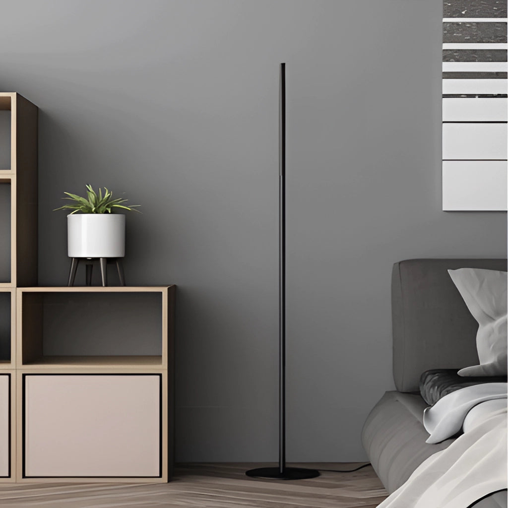 A stylish floor lamp with an avant-garde design, placed in a modern interior setting with wooden floors, a grey rectangular flowerpot, and a touch of greenery from a plant.