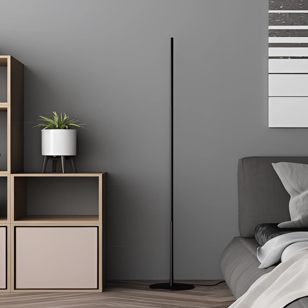 A modern floor lamp with an avant-garde design placed in a stylish living room featuring grey flooring, a wooden plant stand, and a comfortable grey couch.