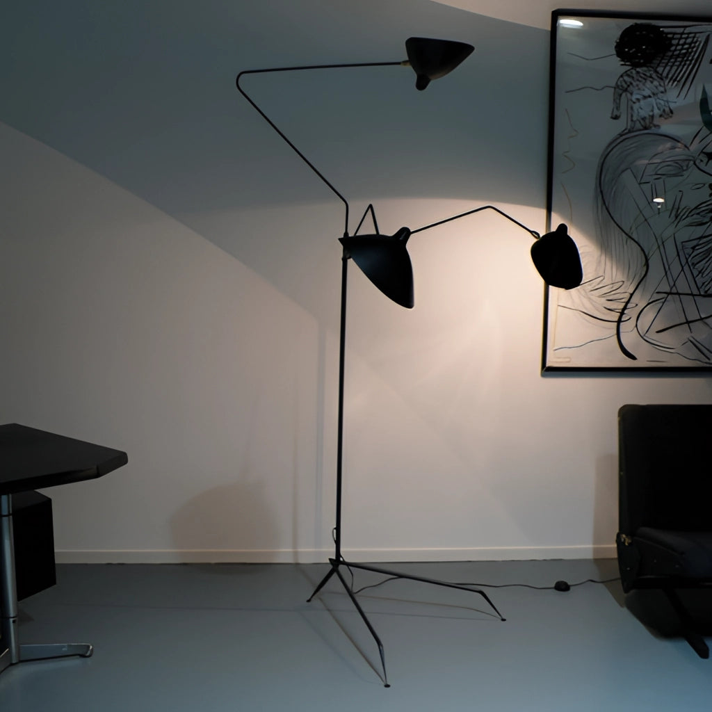 Floor lamp with tripod base and directional light in a modern interior design setting with wooden flooring and neutral wall tones.