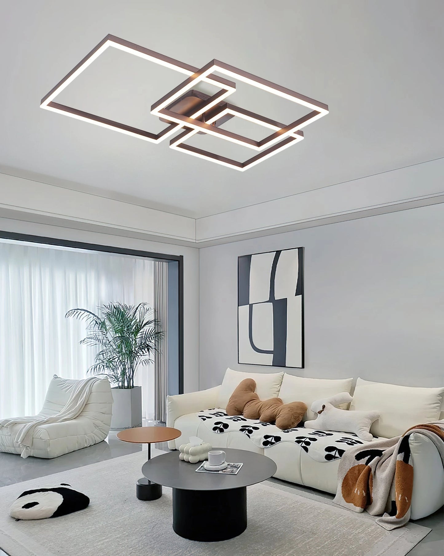 Modern living room featuring a geometric aluminum pendant light with LED technology, illuminating a cozy area with a grey couch, wooden elements, and large windows.