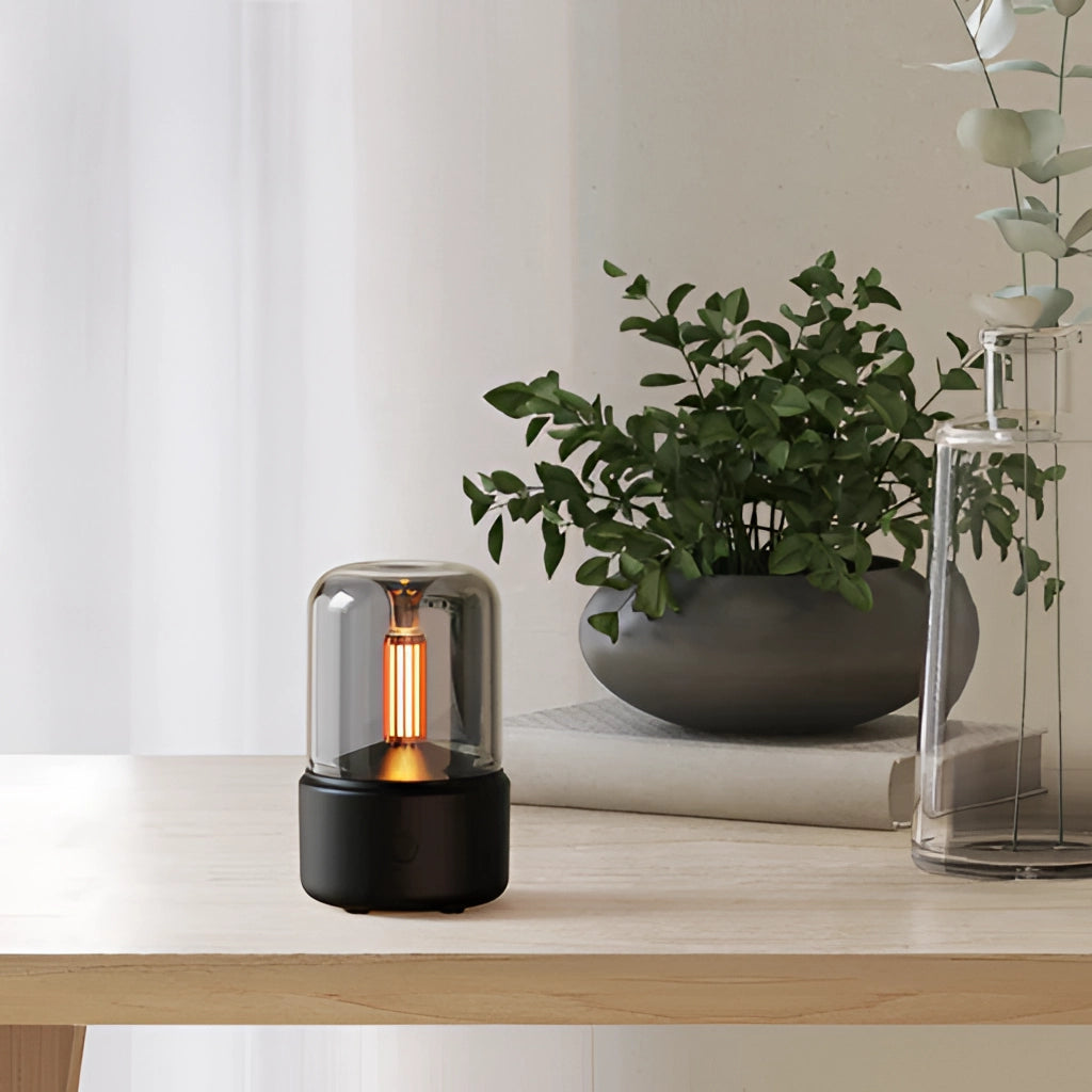 LED Aromatherapy Diffuser with Candle Light Effect on a wooden surface next to a potted houseplant and a vase in a modern interior setting.
