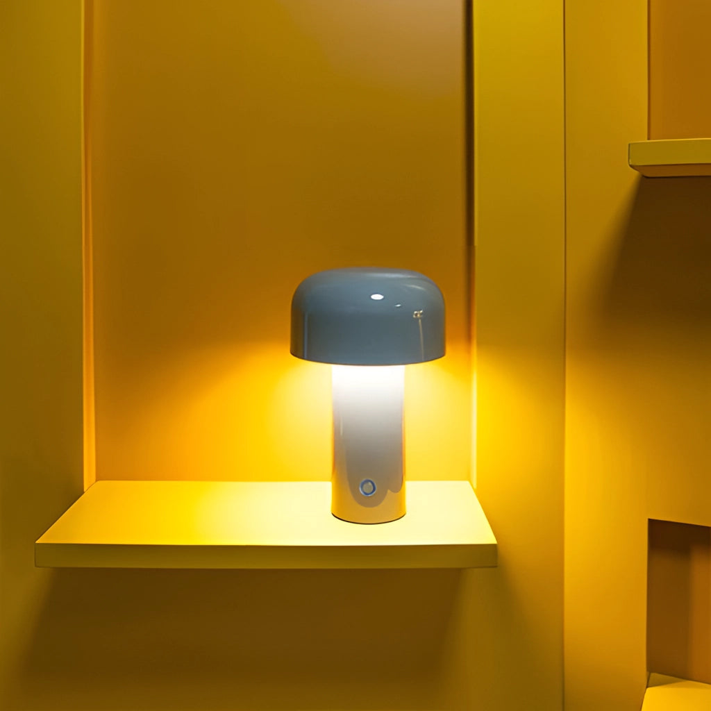 LED cordless table lamp with a unique mushroom design placed on a wooden shelf in a room with various lighting accessories and decor.