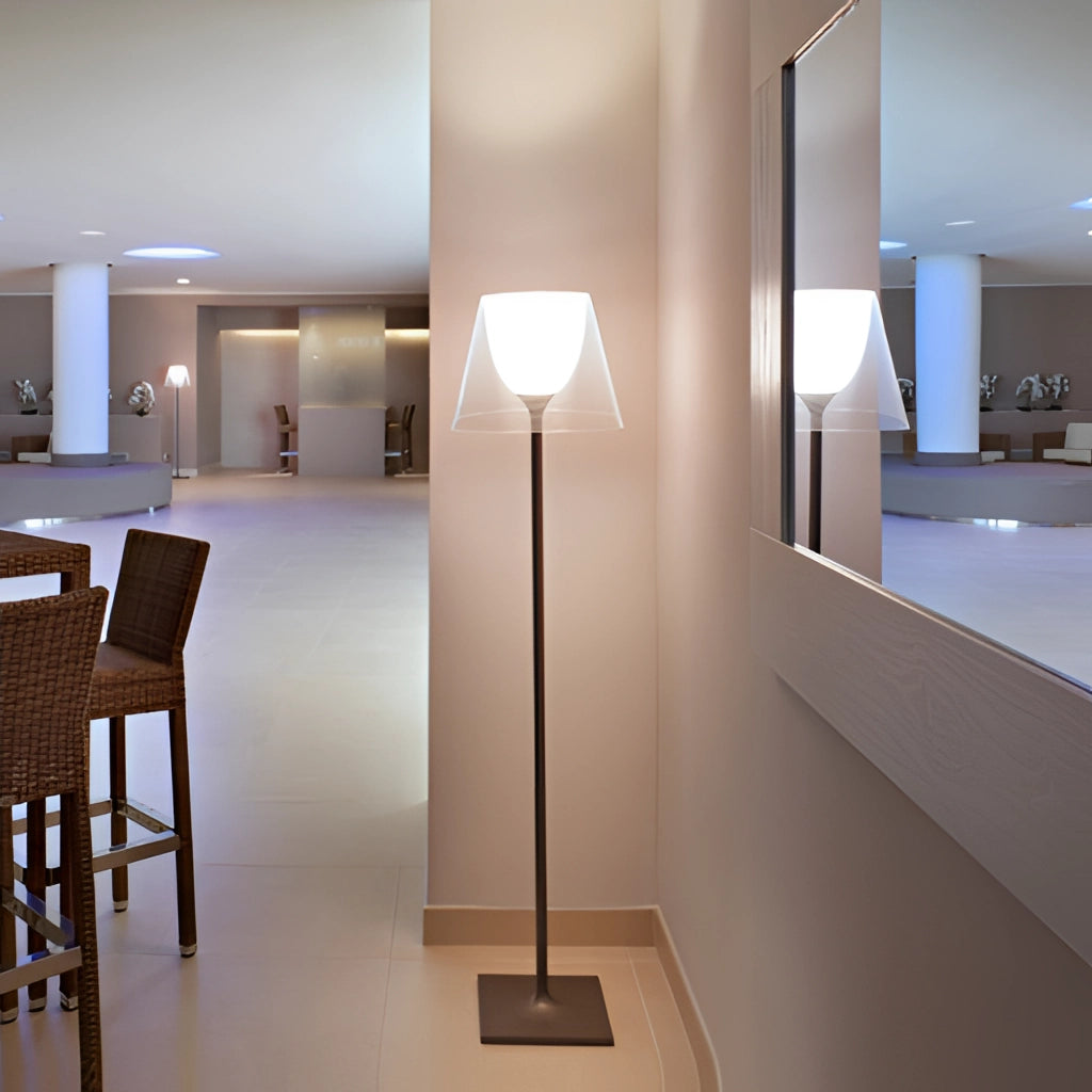 LED floor lamp with amber, clear, and gray downward shade, positioned in a modern interior setting with wooden furniture and architectural elements.