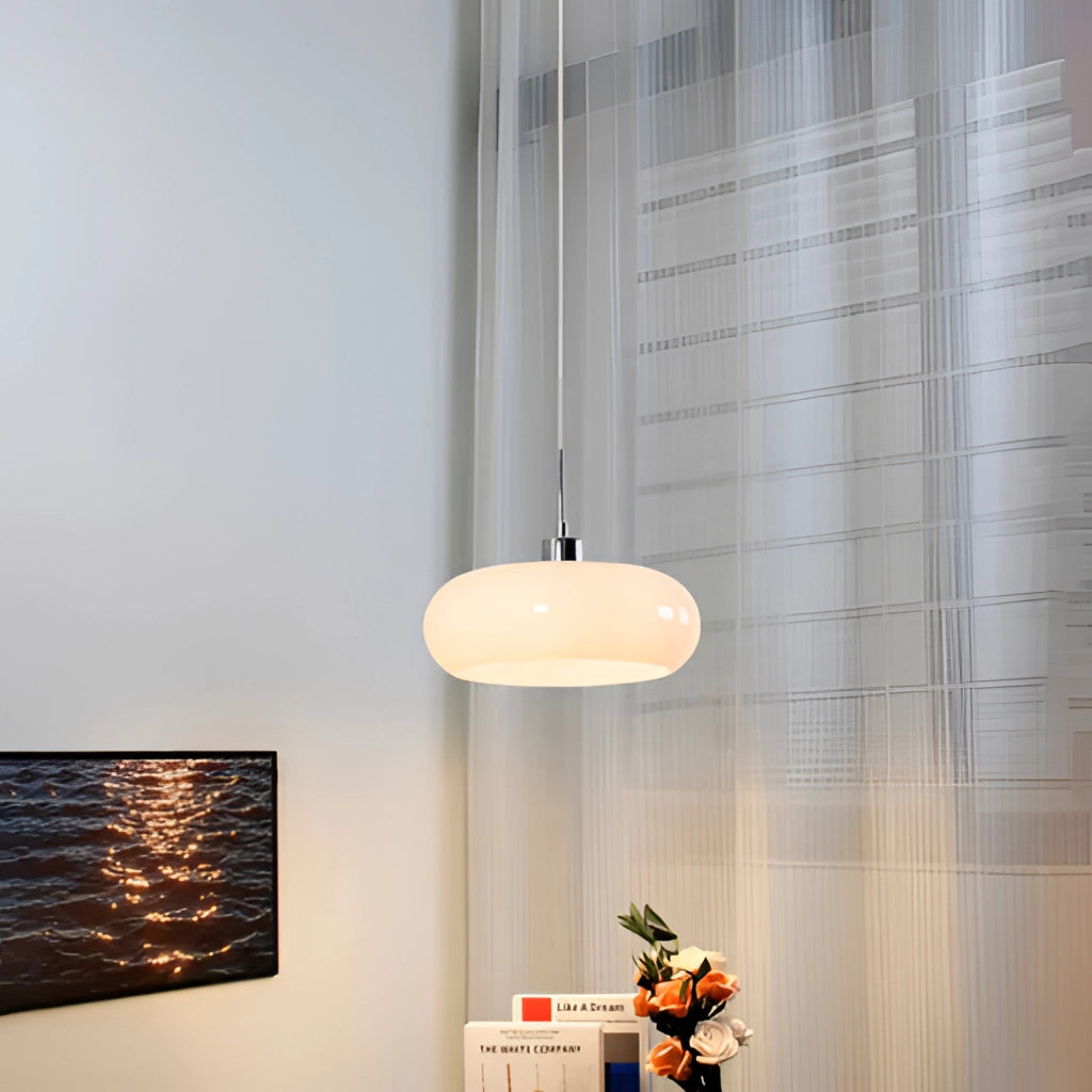 Luxury modern style chandelier with LED bulbs, Jaxon glass pendant light, hanging from a ceiling, with a wooden and minimalist interior background featuring a wall, houseplants, and modern art.