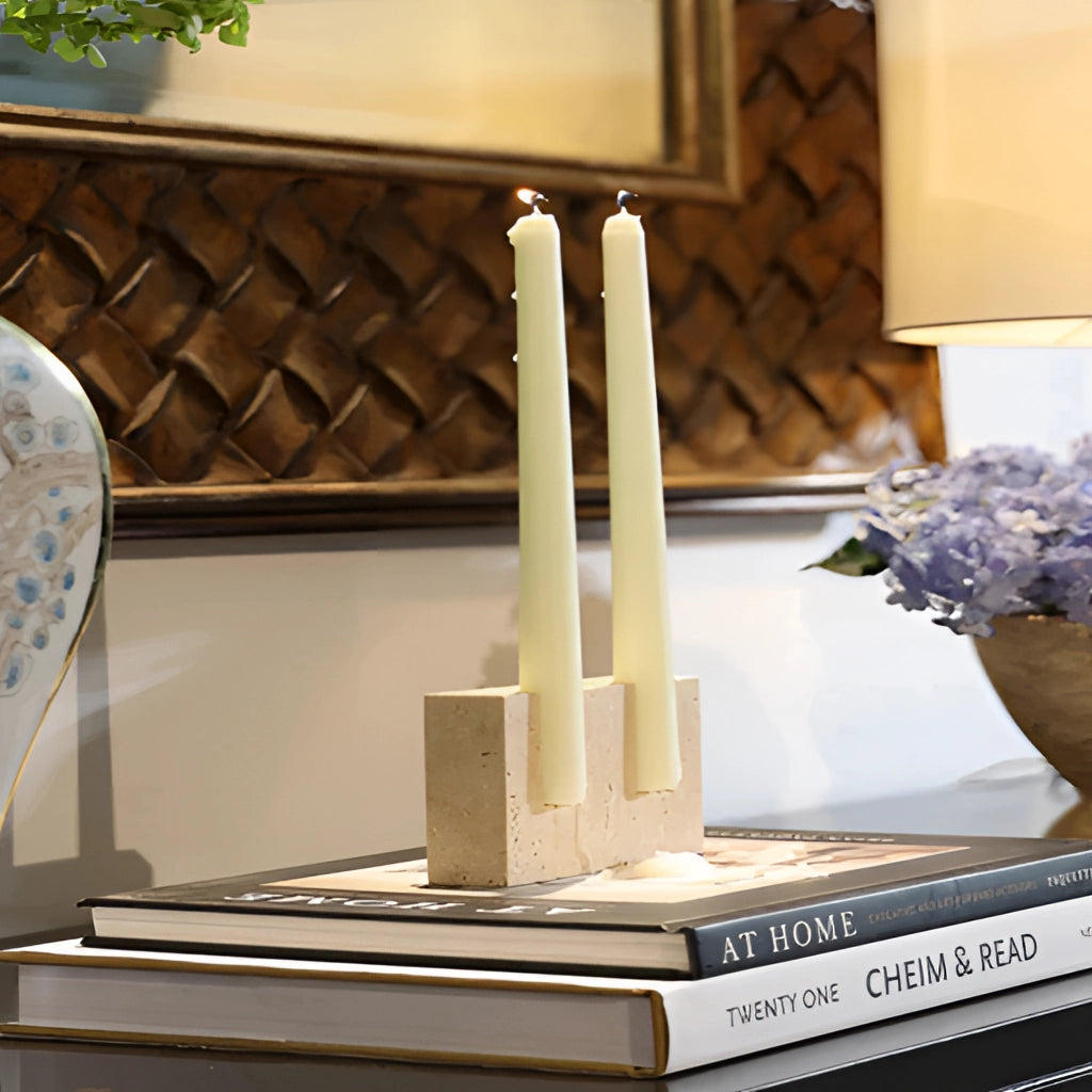 Marble candle holder displaying a lit wax candle, ideal for weddings and parties, placed in a room with wooden elements and plants in the background.