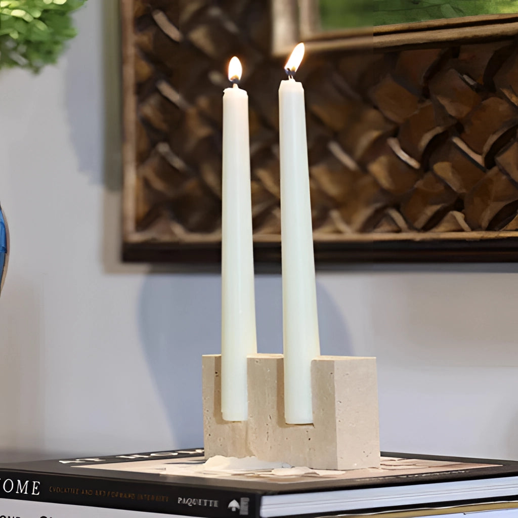 Marble candle holder with a lit candle, surrounded by elegant interior design elements including wooden furnishings and a small plant.