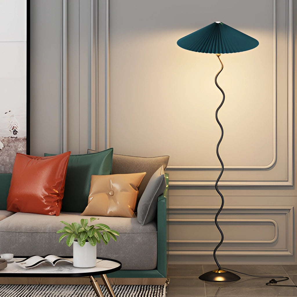 A curved pleated floor lamp with a metal textile shade, standing on a wooden base, illuminating a modern interior setting.