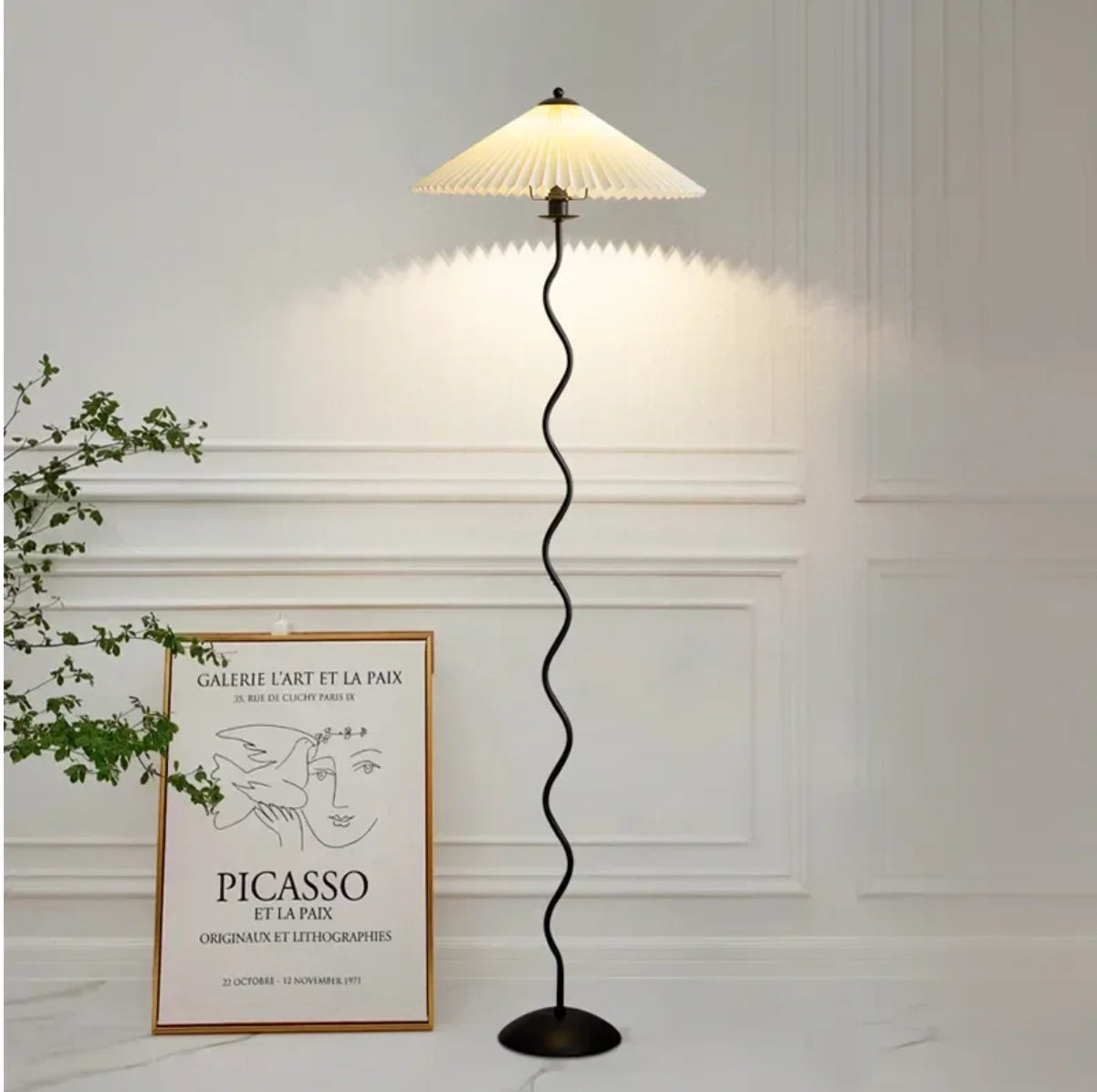 A modern metal textile curved pleated floor lamp with a rectangular shade and wooden base.
