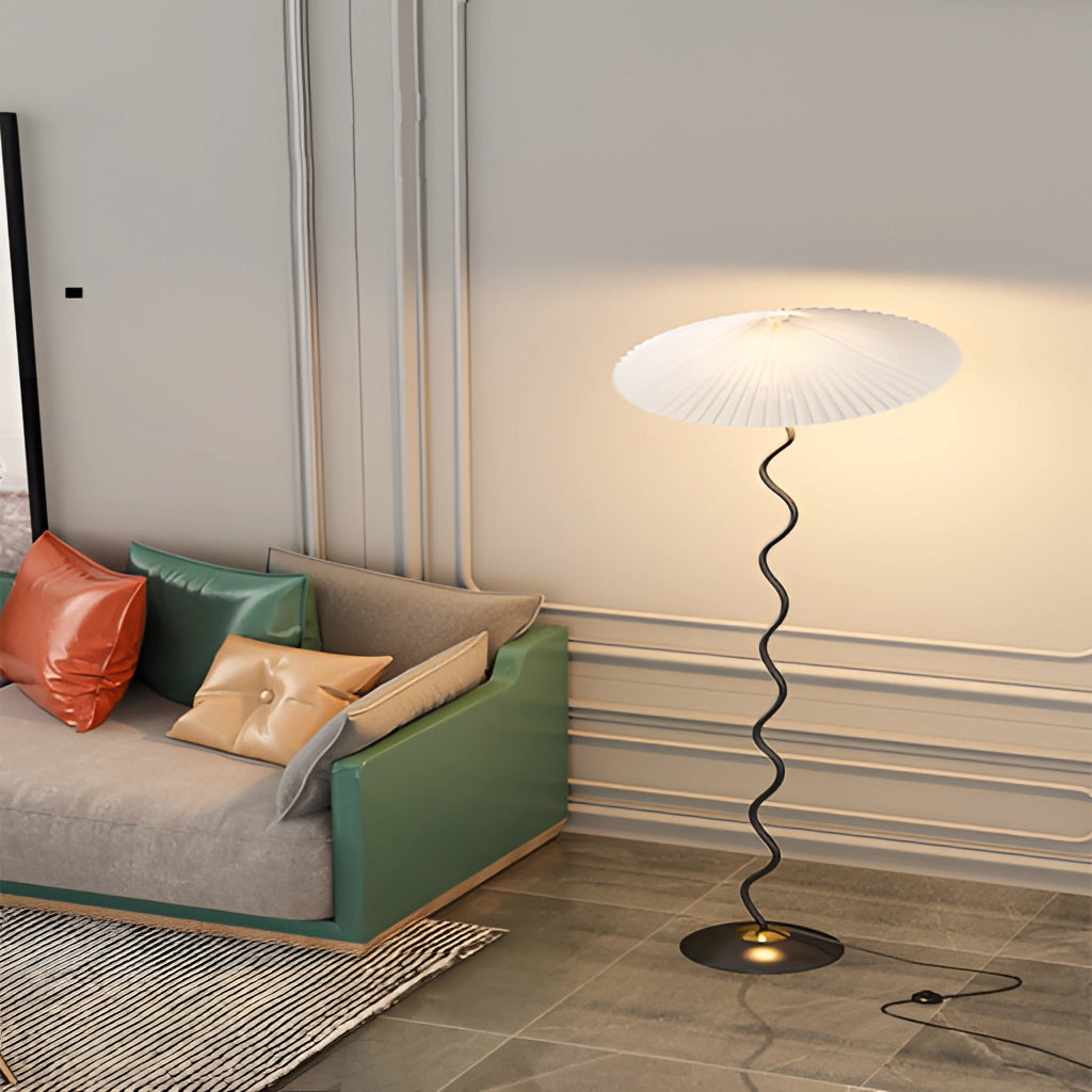 A stylish Metal Textile Curved Pleated Floor Lamp positioned on a wooden floor next to a comfortable couch.