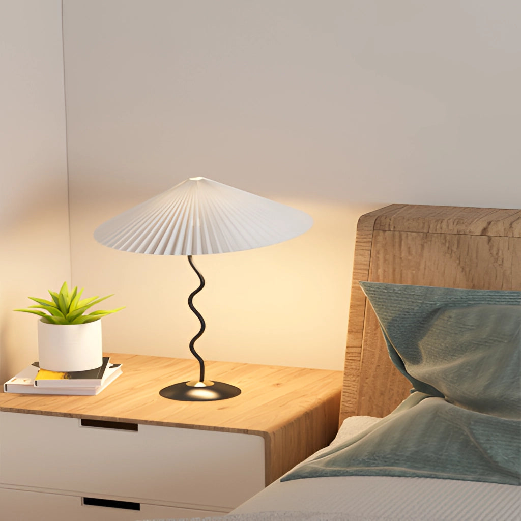 Metal Textile Curved Pleated Floor Lamp with a shade, standing on a wooden floor next to a houseplant.