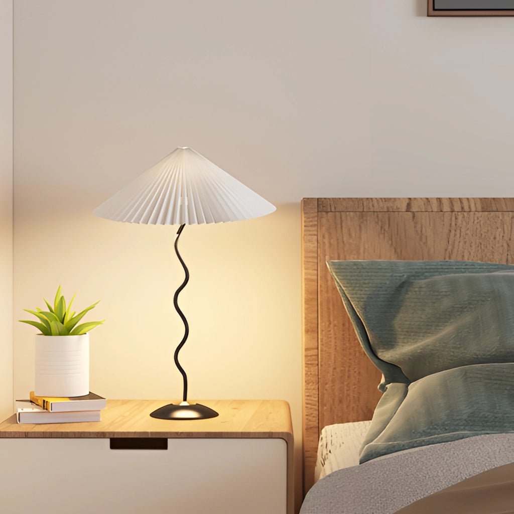 Metal Textile Curved Pleated Floor Lamp placed in a cozy interior setting featuring wooden elements, a table, a plant, and ambient lighting.
