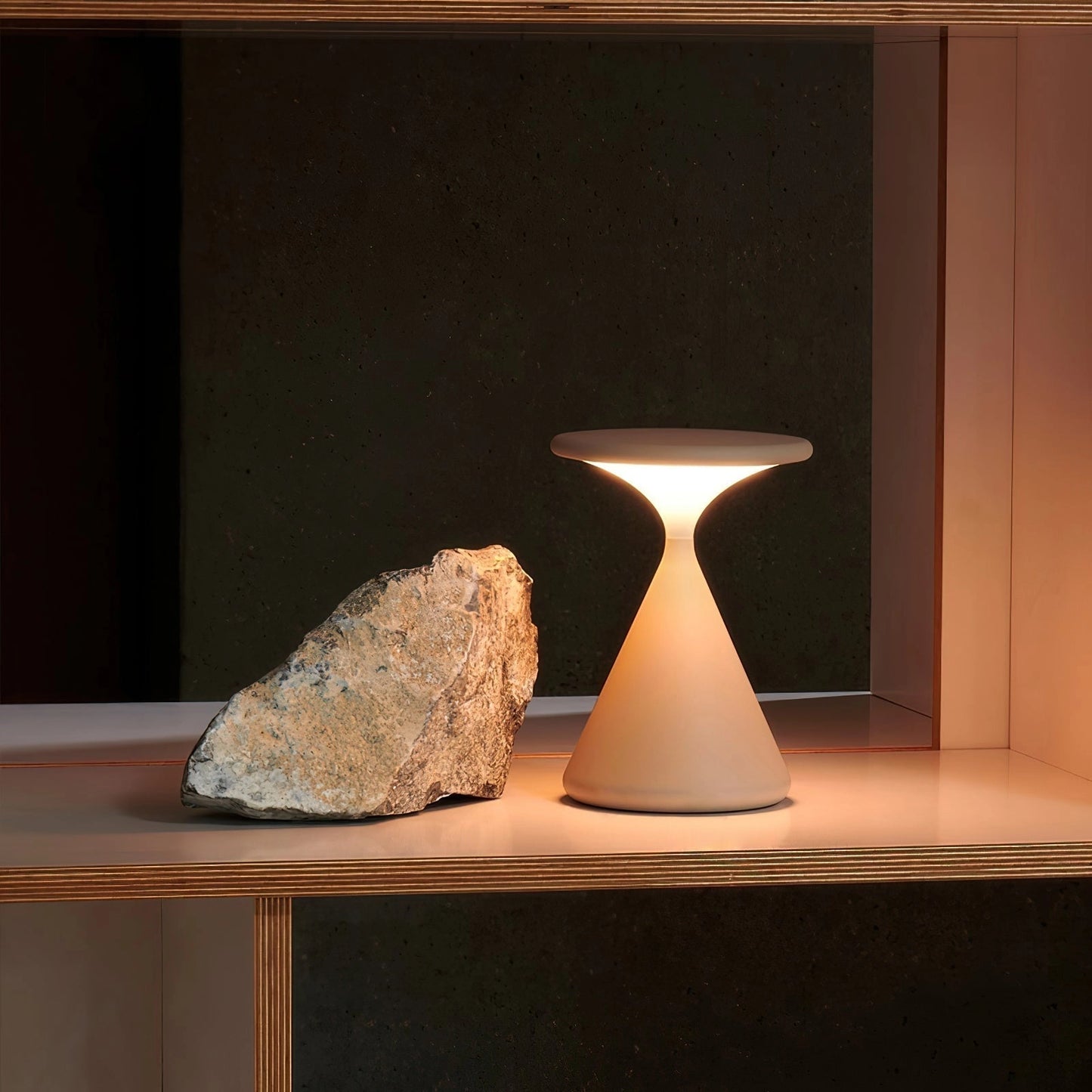 A versatile and elegant Selene outdoor cordless lamp placed on a wooden rectangular table, providing portable ambiance.