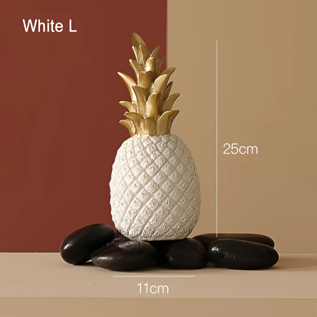Golden resin pineapple-shaped ornament for home decor, shown in a white large variant, placed next to a houseplant and wooden surface.