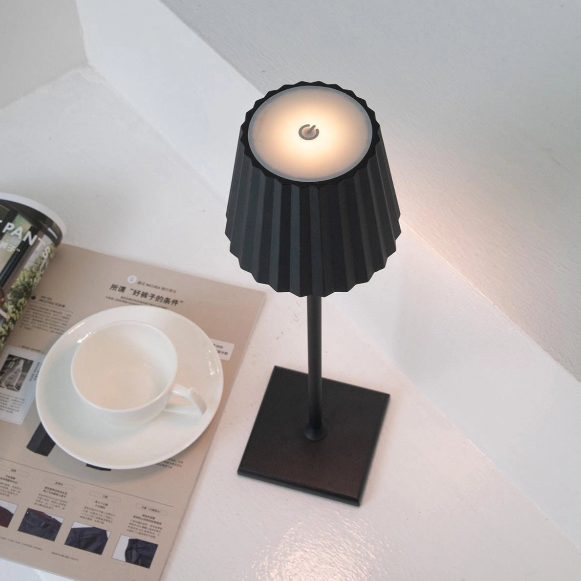 Cordless LED table lamp with stepless dimming and quick charging, placed on a table along with tableware and kitchen utensils.
