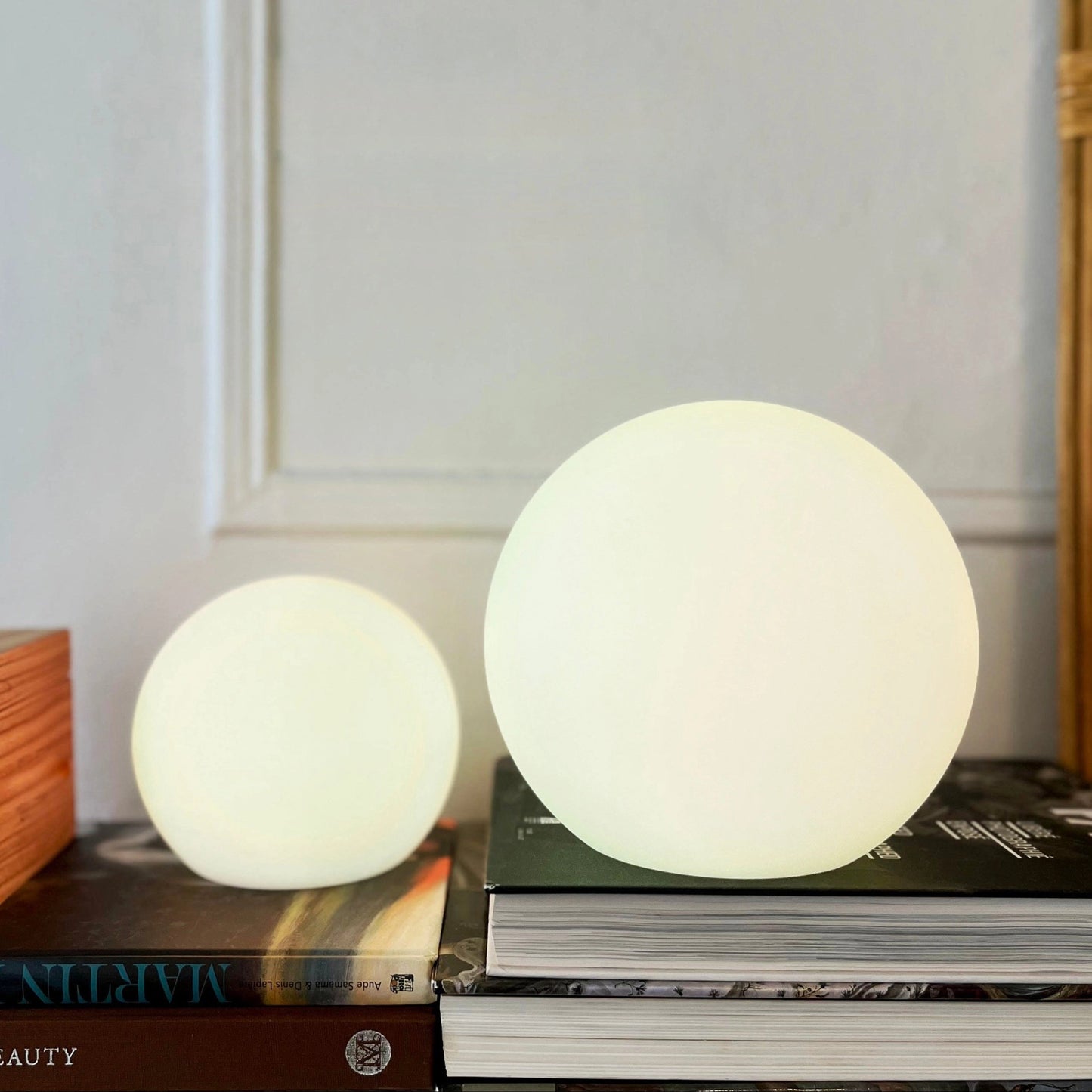 Rechargeable Cordless LED Moon Table Lamp with 16 Color Options, 6 inches, placed on a wooden table with shelving and hardwood flooring in the background.