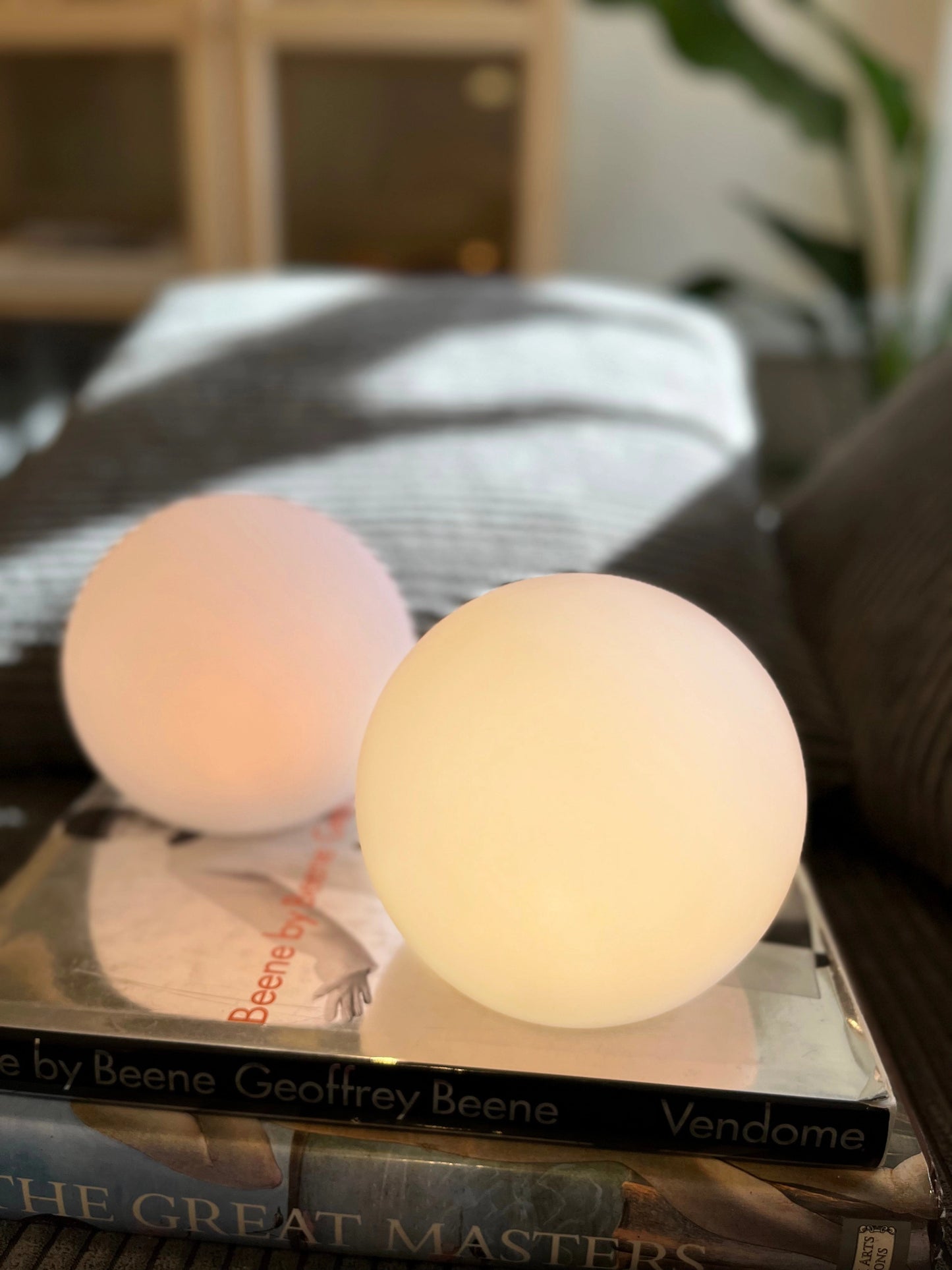 Rechargeable cordless LED moon table lamp with 16 color options placed on a wooden table next to a plant and dishware.