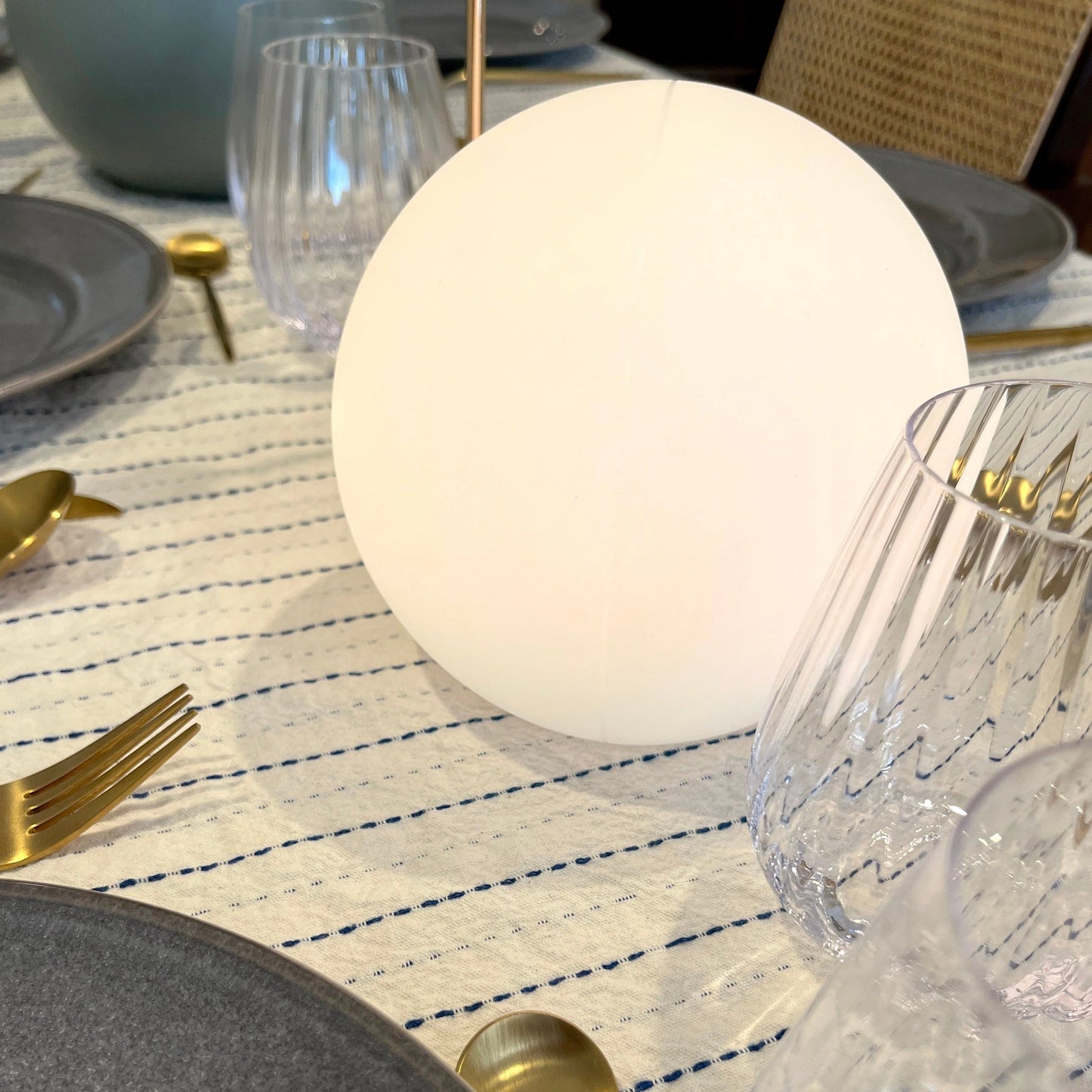 Rechargeable Cordless LED Moon Table Lamp - 16 Color Options, 8 inches, displayed on a table with various tableware including plates, cutlery, and glasses.