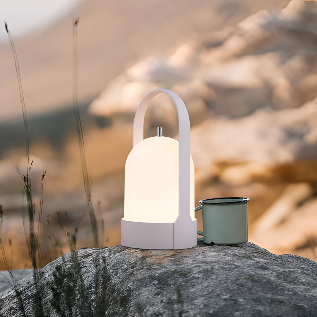 Rechargeable table lamp with touch dimming, placed on a wooden surface, with a softly illuminated background featuring a winter landscape and trees.