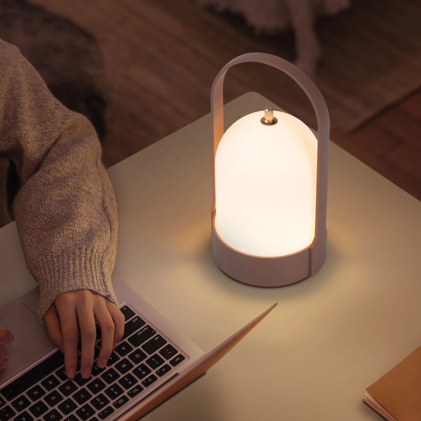 Rechargeable table lamp with touch dimming feature placed on a wooden desk beside a laptop and other office equipment.