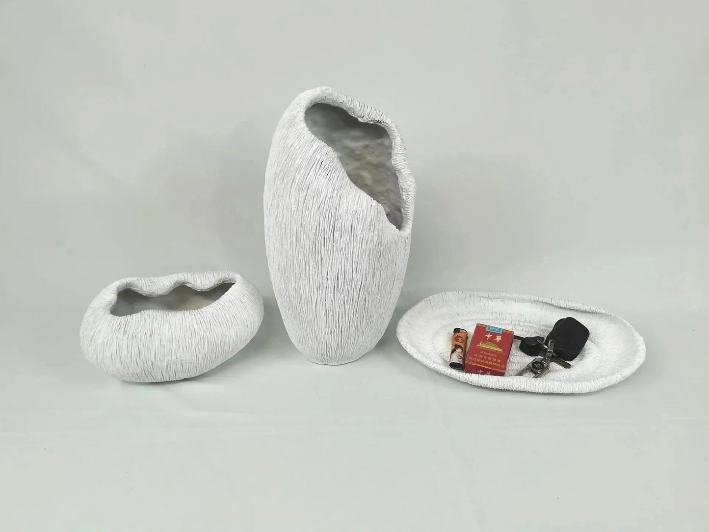 A grey, nature-inspired decorative bowl made of resin, featuring a wood-like texture and artistic design, placed on a rectangular surface.