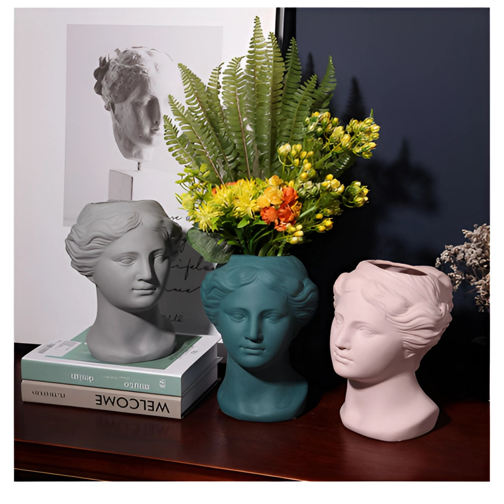Neoclassical Venus head vase sculpture in blush pink, used as a planter with flowers.