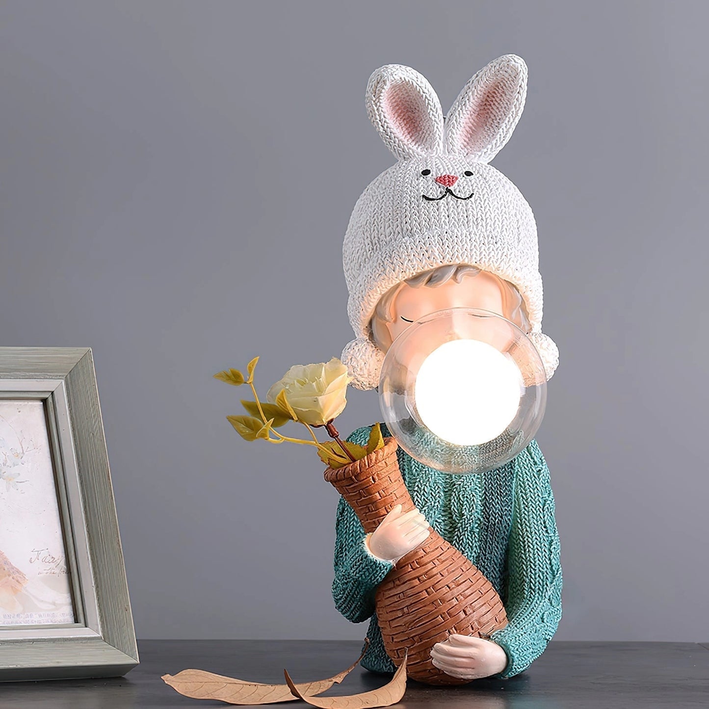 Resin table lamp featuring an elegant rabbit girl design with dual glass lampshades, wearing a white costume hat and sitting, placed next to a picture frame.