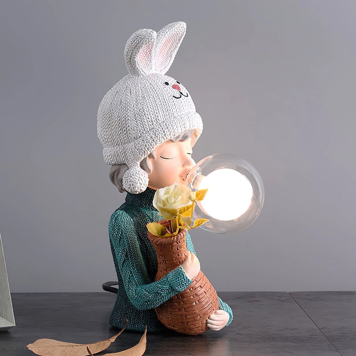 Resin table lamp featuring an elegant rabbit girl design with dual glass lampshades, the figure is depicted sitting and wearing a knit cap.