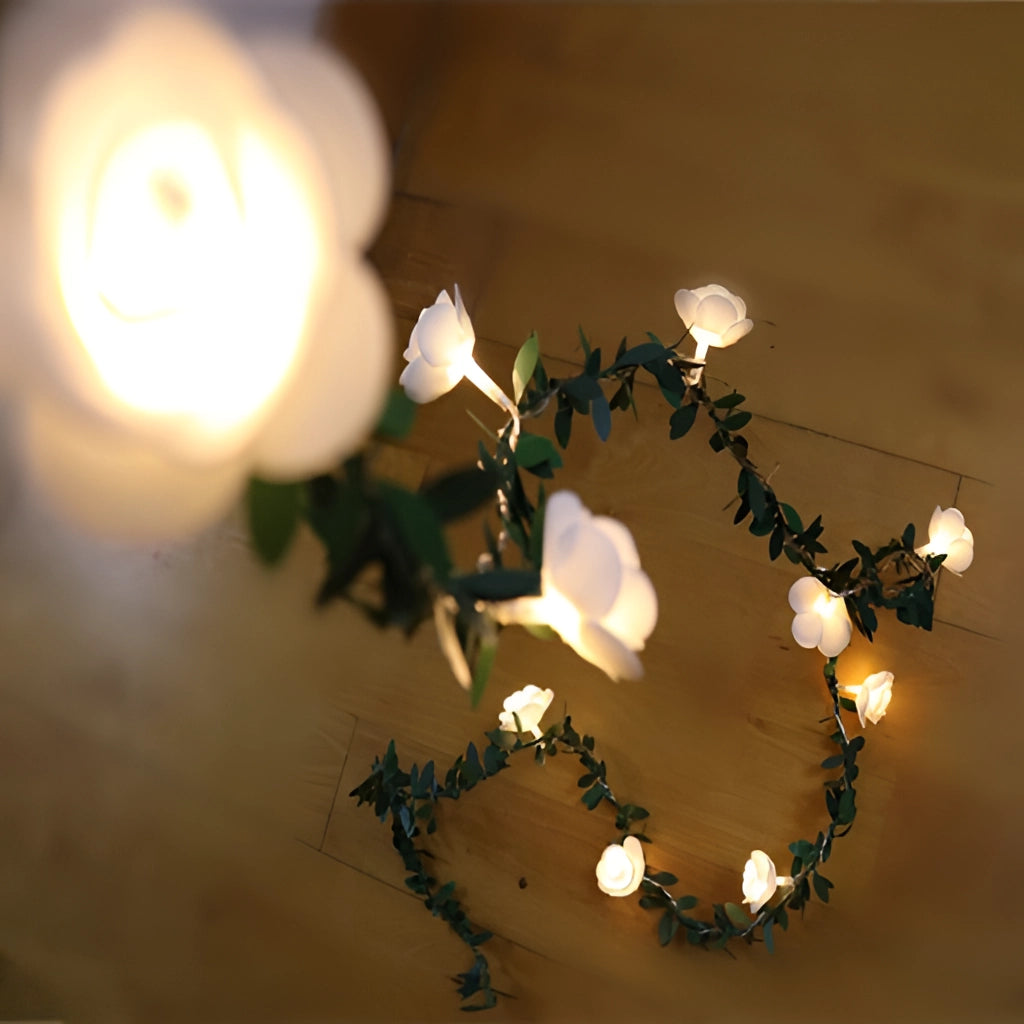 Battery Operated LED Garland Rose Flower String Lights hanging in a dark setting, showcasing detailed faux rose petals and branches.