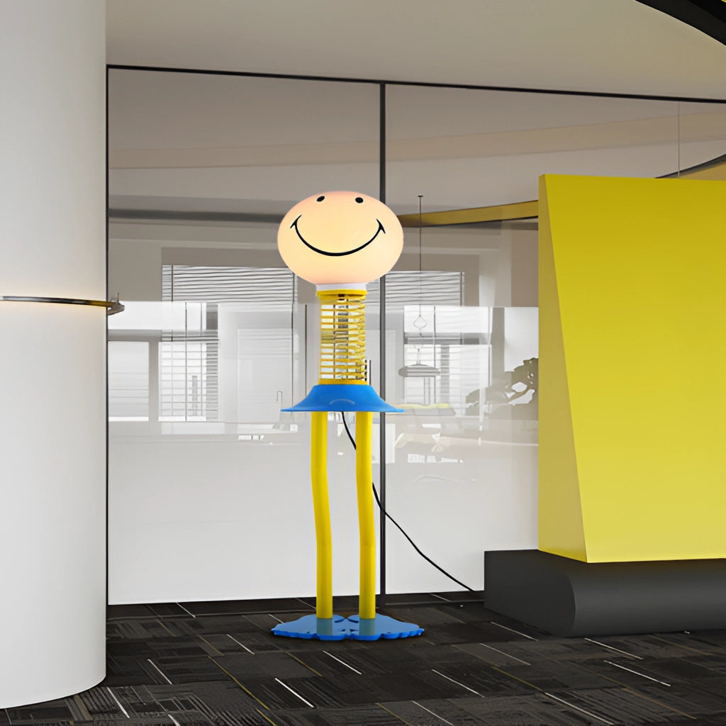 Yellow, blue, and white smiley face design floor lamp made of metal iron and acrylic glass, featuring an LED bulb, placed in a modern bedroom setting with wooden flooring and neutral wall colors.