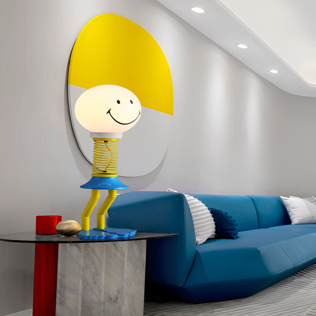 Smiley face design floor lamp featuring yellow, blue, and white colors, made of metal iron and acrylic glass, with an LED bulb and 110V US plug, illuminating a bedroom interior with a couch and wall decor in the background.