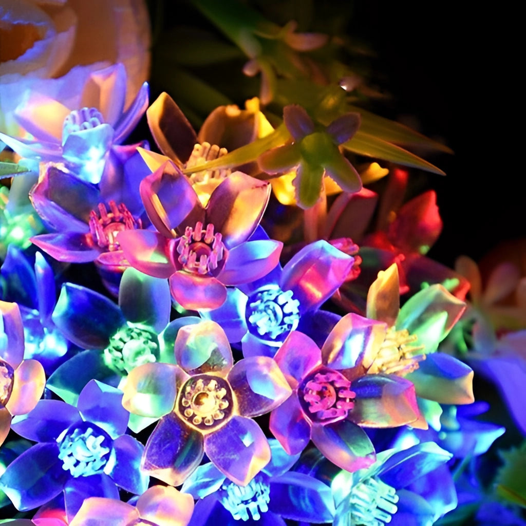 Solar Flower Garden LED Light Strips illuminating vibrant purple flowers amidst lush green plants in a garden setting.