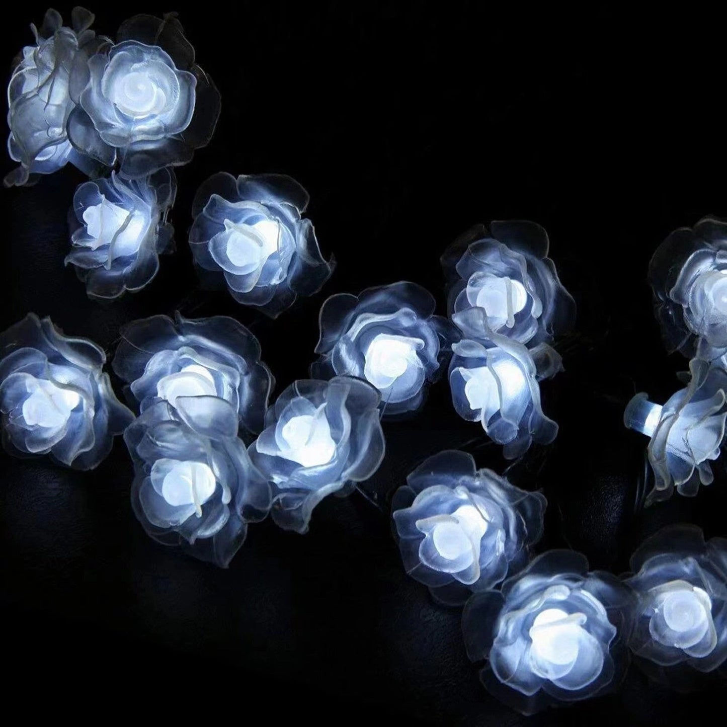 White rose shaped solar-powered LED light strips illuminating a garden at night.