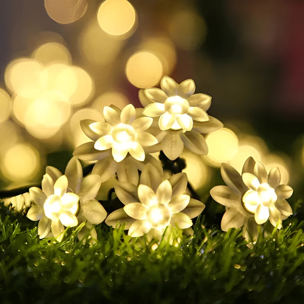 Lotus flower-shaped solar LED light strips in a garden setting with vibrant petals and greenery, showcasing a close-up of the flowering plant among grass.
