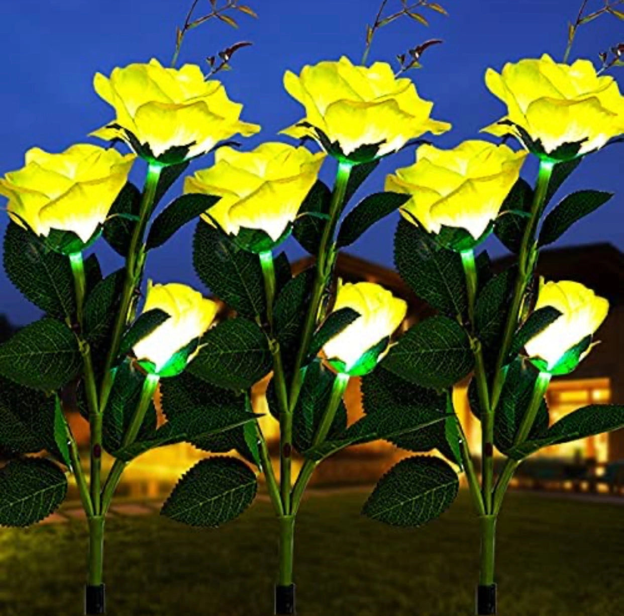 Solar LED Rose Lights Twin Pack in Yellow, illuminating a garden with lifelike yellow rose flowers amidst greenery.