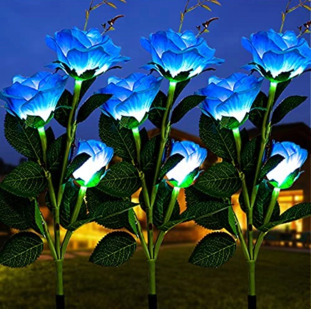 Outdoor garden featuring a twin pack of solar-powered LED rose lights in blue, surrounded by vibrant green leaves and foliage against a clear sky.