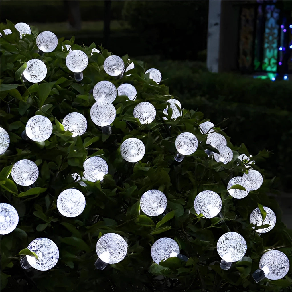 Solar String Lights - IP65 Waterproof RGB/White LEDs illuminating a dark outdoor space with grass in the background.