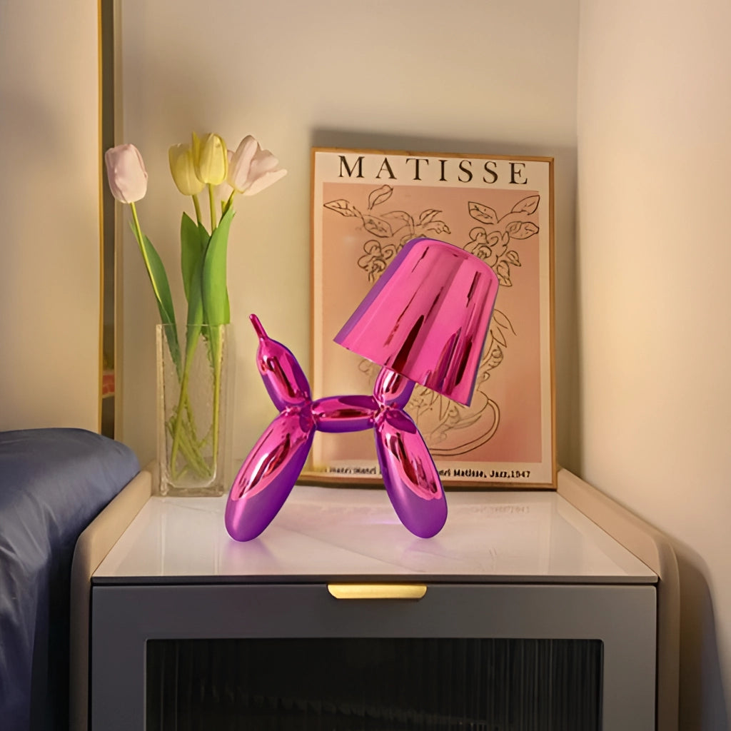 Crystal table lamp with touch-sensitive dimmable feature, balloon dog design, placed on a wooden table with a purple and pink flower plant nearby.