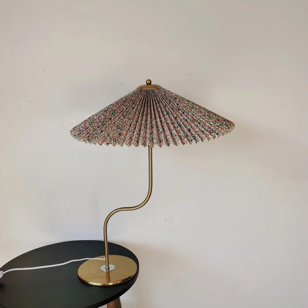 A table lamp with a yellow diamond-patterned shade, featuring flower designs, and a dark green base.