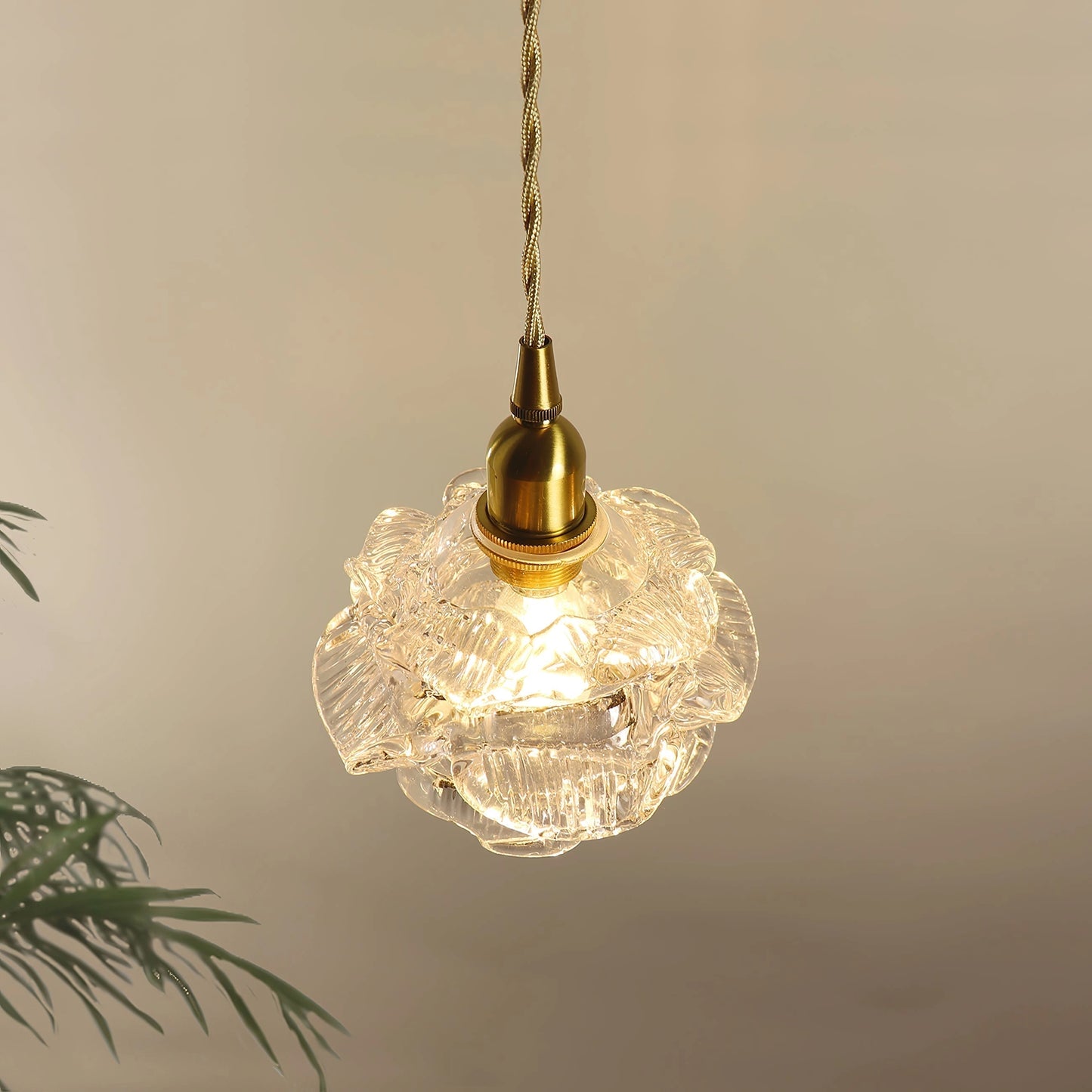Vintage brass wall light with a rose glass shade, elegantly designed wall sconce featuring ornate metal detailing and a circular base.